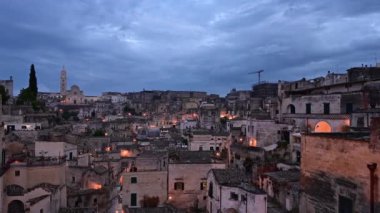 Matera, Basilicata, İtalya. Ağustos 2021. Matera 'nın Sassi' sine doğru geniş açılı objektifle mavi saatte çekilen çekim. Evlerin düzensizliği, arka planda katedral..