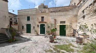 Matera, Basilicata, İtalya. Ağustos 2021. Tarihi merkezde, tufa kayası bloklarıyla inşa edilmiş evlerden oluşan bir avlunun kamera görüntüleri. Matera taşlarının kentsel manzarası.