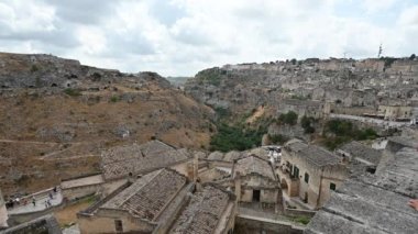 Matera, Basilicata, İtalya. Ağustos 2021 'de San Pietro Caveoso Kilisesi ve sağdaki Santa Maria di Idris Rock Kilisesi ile birlikte. Merkezde, Matera Kanyonu. Soldaki kaya mağaraları.