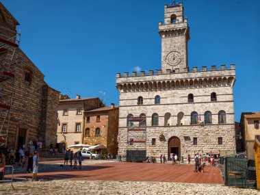 Montepulciano, Toskana, İtalya. Ağustos 2021. Piazza grande tarihi merkezin ana meydanıdır, belediye binası kuleye bakar ve saat kanıttır. Meydandaki insanlar.