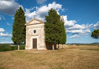 San Quirico d 'Orcia, Toskana, İtalya. Ağustos 2020. Güneşli bir günde Madonna di Vitaleta 'nın büyüleyici şapeli. Beyaz bulutlu mavi gökyüzü. Hiç kimse. Boşluğu kopyala.