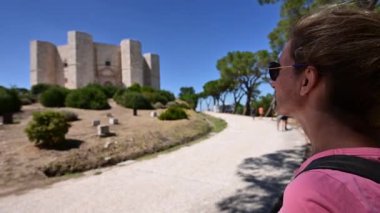 Andria, Puglia, İtalya. Ağustos 2020. Orta yaşlı bir kadın akıllı telefonuyla Castel del Monte 'de fotoğraf çekiyor. Orijinal sekizgen şekli panoramaya hakim. Kadına odaklan..