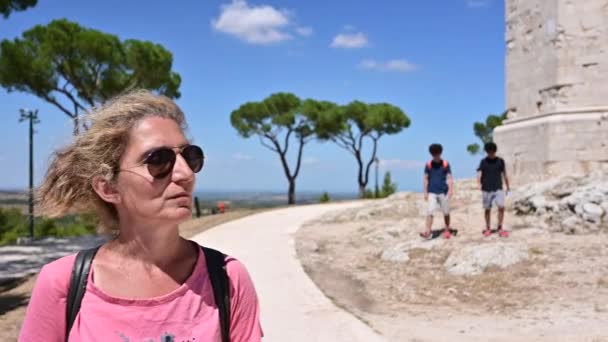 安德里亚 普利亚 意大利 2021年8月照片上有一个中年妇女的画像 她戴着太阳镜在蒙特城堡附近的路上行走 观察着它 在后台有两个男孩 — 图库视频影像