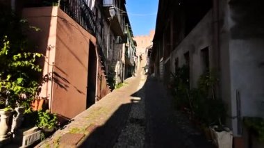 Montemagno, Piedmont, İtalya. Pov görüntüleri tepenin üstündeki kaleye giden ara sokaklardan birinde yürüyor. Yanımızda köyün evleri akıyor..