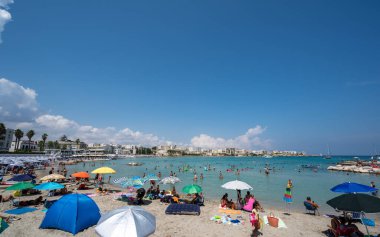 Otranto, Puglia, İtalya. Ağustos 2021. Rıhtımın muhteşem manzarası, insanlar manzaranın tadını çıkarmak için duvar boyunca duruyorlar. Güzel bir yaz günü.