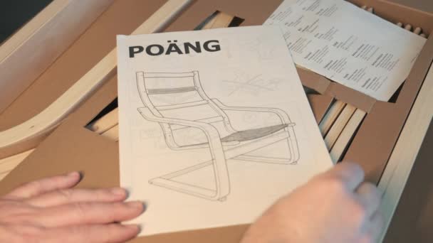 意大利皮埃蒙特都灵 2021年12月一张长椅包装的特写镜头 一只手在组装指南手册中留下叶子 — 图库视频影像