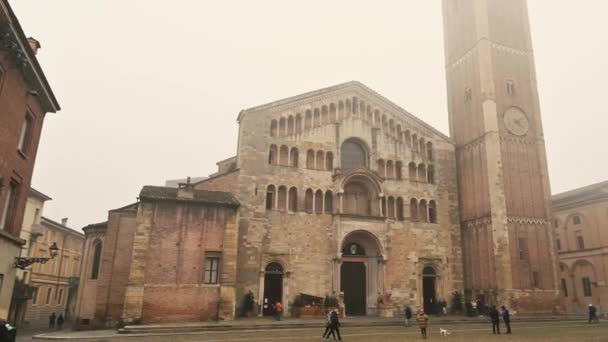 イタリア エミリア ロマーニャ州パルマ出身 2022年1月 霧に包まれたドゥオモ広場の素晴らしいパンの映像 大聖堂と洗礼堂がシーンを支配し 人々は広場を横断します — ストック動画