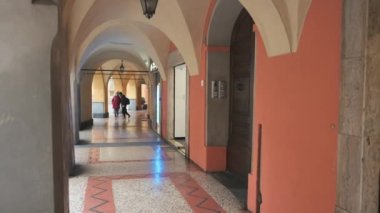 Parma,Emilia-Romagna,Italy.January 2022.Footage under the arcades of the historic center.A middleaged woman and a boy stroll under the arches. They have masks to defend themselves from the coronavirus
