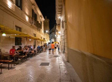 Lecce, Puglia, Italy. August 2021. Nightlife in the historic center: along the streets the tables of the clubs with customers.