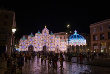 Lecce, Puglia, İtalya. Ağustos 2021. Koruyucu aziz Sant 'Oronzo' nun ziyafeti vesilesiyle tarihi merkeze parlak süslemeler yapıldı. İnsanlar onları izler ve resimlerini çeker.