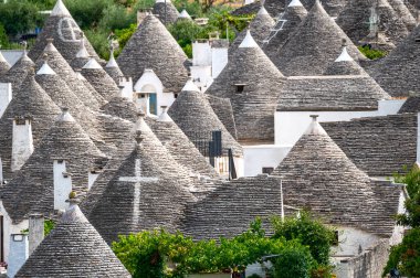 Alberobello, Puglia, İtalya. Ağustos 2021. Büyüleyici tarihi köyün inanılmaz hava görüntüleri. Yukardan, aşikar şehir manzarası konik taş çatılarla karakterize edilir. Ara sokaklardaki insanlar