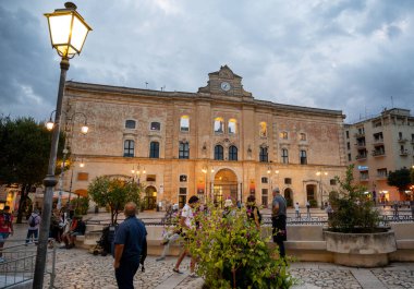 Matera, Basilicata, İtalya. Ağustos 2021. Piazza Vittorio Veneto 'nun mavi saat manzarası inanılmaz. İnsanlar içinden geçiyor..