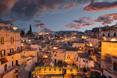 Matera, Basilicata, İtalya. Ağustos 2021. Matera 'nın Sassi' sine doğru geniş açı mercekli mavi saat manzarası. Evlerin düzensizliği, arka planda katedral..