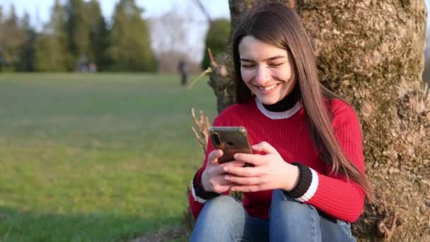 Приваблива Молода Брюнетка Сидить Біля Підніжжя Дерева Парку Вона Отримує — стокове відео