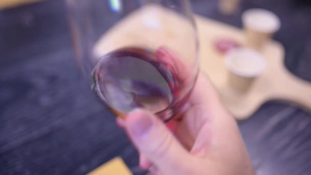 赤ワインと試飲ガラスのクローズアップスローモーション映像 ガラスの回転は ワインの表面を波打つと背の高いガラス壁に沿って広がっています 試飲と良い生活の概念 — ストック動画