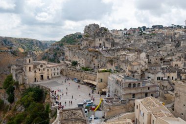 Matera, Basilicata, İtalya. Ağustos 2021. Soldaki San Pietro Caveoso Kilisesi ve sağdaki Santa Maria di Idris Rock Kilisesi 'nin muhteşem manzarası. Taşlardan oluşan şehir manzarası.