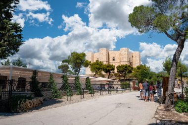 Andria, Puglia, İtalya. Ağustos 2021. Castel del Monte 'nin güzel manzarası. Orijinal sekizgen şekli panoramaya hakim. Bir grup turist deniz çam ağacının gölgesinde mola veriyor..