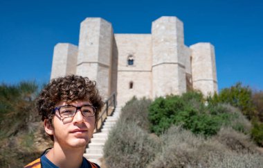 Andria, Puglia, İtalya. Ağustos 2021. Arkasında Castel del Monte 'nin silueti olan genç bir adamın portresi. Güzel bir yaz günü.