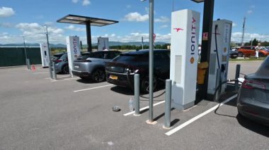 Fransa, Paris otoyolu, Haziran 2022. Bir otoyol dinlenme yerinde, bir grup elektrikli araba hızlı şarj istasyonunda elektrikle dolduruluyor. Arabanın arkasında şarj olan soketi görebilirsiniz.