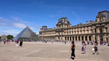 Fransa, Paris, Haziran 2022. Güzel bir günde, Louvre 'un büyük meydanında, büyük cam piramit göze çarpar. İnsanlar avluda yürüyor..