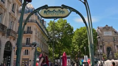 Paris, Fransa, Haziran 2022. Metro tabelasının kendine özgü bir klasik görünüşü var. İnsanlar giriş çıkışlardan girip çıkıyorlar..