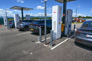 France, highway to Paris, June 2022. At a motorway rest area, a group of electric cars are refueling with electricity at the fast-charging station.
