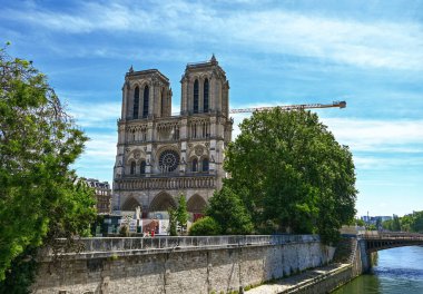 Paris, Fransa. Haziran 2022. Sen nehri üzerindeki köprüden Notre Dame cephesinin güzel bir manzarası var. Restorasyon alanının vinci, katedrale zarar veren büyük yangından sonra görülebiliyor..