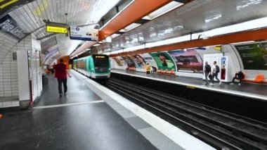 Paris, France, June 2022. A convoy arrives at a metro stop: it comes out of the tunnel and stops three tourists with backpacks get on board.