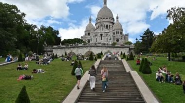 Paris, France, June 2022. Amazing POV footage on the steps leading to the Sacre Coeur basilica, as we climb the steps in front of us three tourists walk ahead of us. Beautiful summer day.