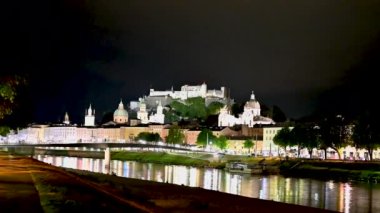 Salzburg, Avusturya, Ağustos 2022. Eski kasabanın büyüleyici gece manzarası. Bir fırtına yaklaşıyor ve gökyüzünü maviyle aydınlatan birkaç yıldırım var. Tepenin tepesindeki kale göze çarpıyor..