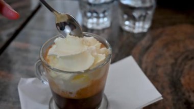 Viyana, Avusturya, Ağustos 2022. Viyana spesiyalitesinin yavaş çekim görüntüleri: kremalı kahve. Kaşıklı el biraz almak için krema içine batar..
