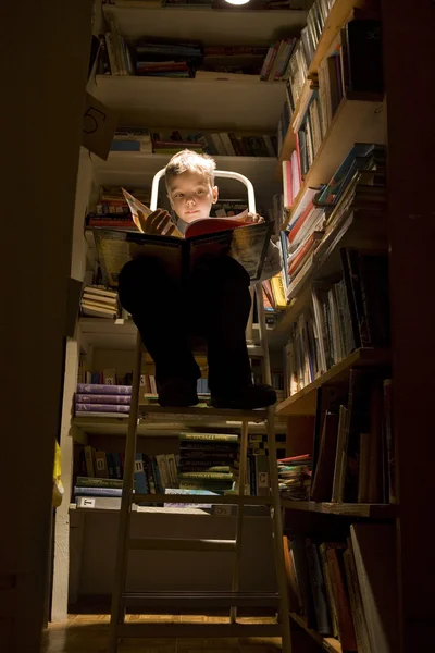 Сhild reading the book in the library Imagine de stoc