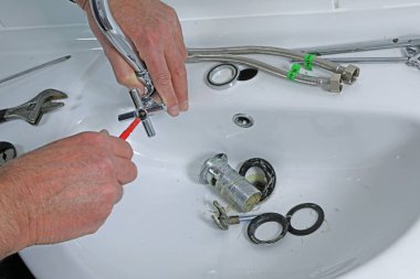 Bir tesisatçı eski musluğu ve atığı bir lavabodan temizliyor..