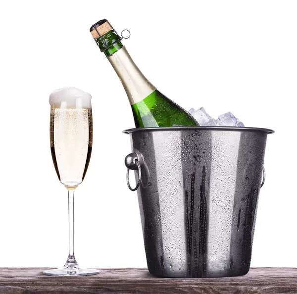Стекло и бутылка шампанского в ведре со льдом — стоковое фото