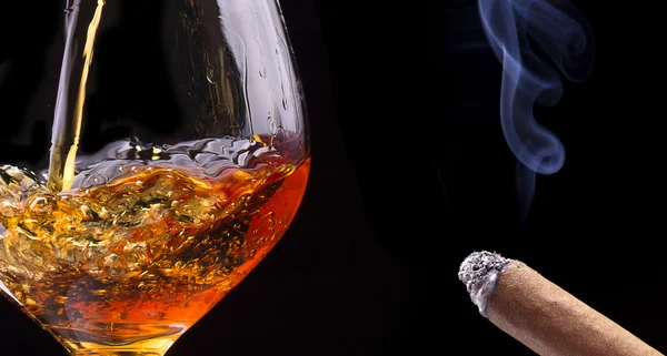 Coñac o brandy en un negro con humo de cigarro — Foto de Stock