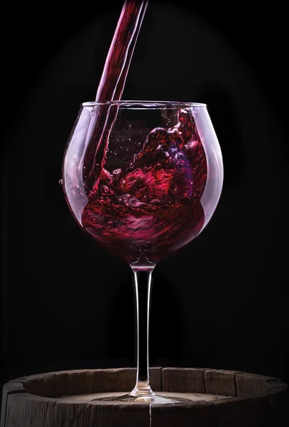 Elegantes Rotweinglas auf schwarzem Hintergrund — Stockfoto