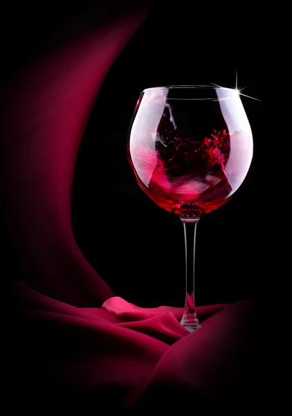 Glass of splashing wine with red silk — Stock Photo, Image