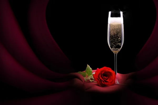 Champagne glas op zwarte en rode zijde met bloem — Stockfoto