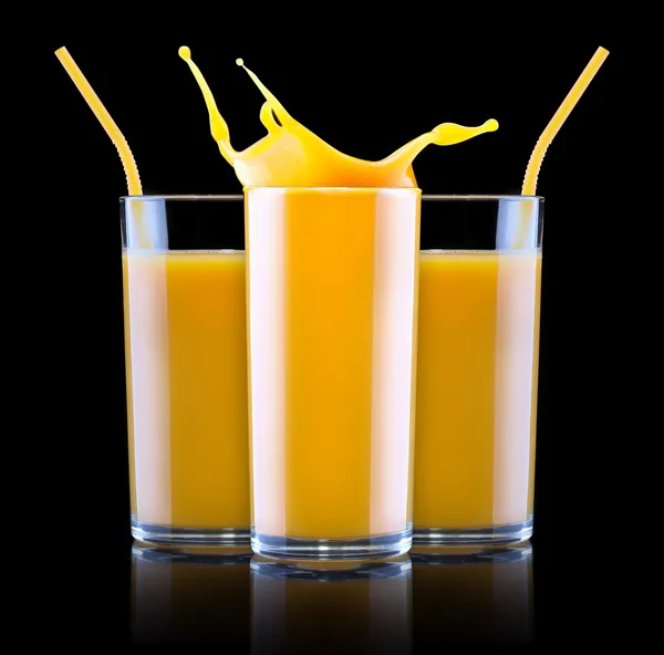 Färsk apelsinjuice i glas med färgstänk — Stockfoto