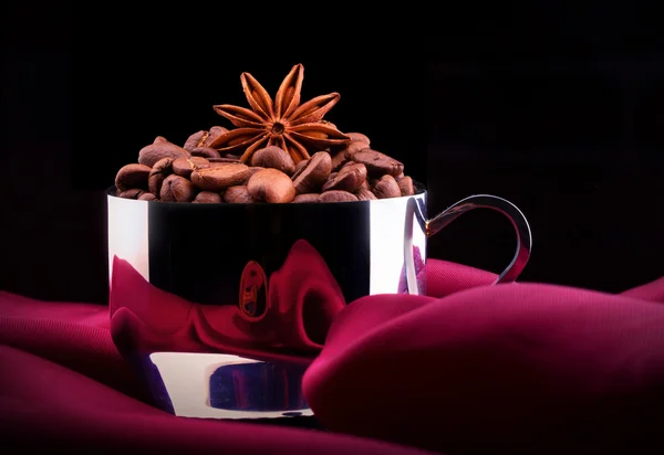 Taza de café con frijoles sobre seda roja —  Fotos de Stock