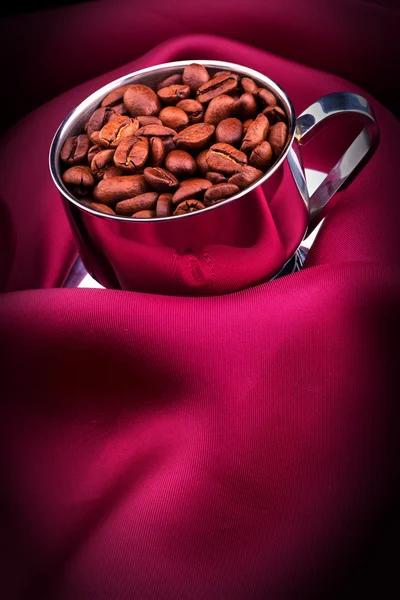 Kopje koffie met bonen op rode zijde — Stockfoto