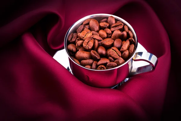 Kopje koffie met bonen op rode zijde — Stockfoto