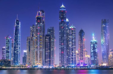 Geceleri Dubai Marina Körfezi 'nin modern binaları. Arka planda ışıklar, Palm Jumeirah, BAE manzaralı.