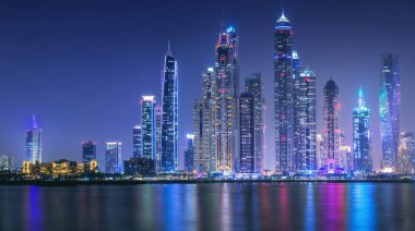 Geceleri Dubai Marina Körfezi 'nin modern binaları. Arka planda ışıklar, Palm Jumeirah, BAE manzaralı.
