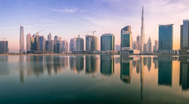 Dubai 'nin şehir manzarası ve panoramik Business Bay manzarası ve sabahları gökdelenlerin su üzerindeki yansıması, BAE.
