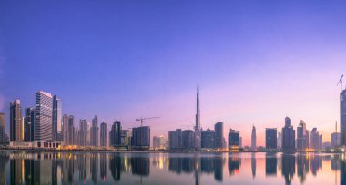 Dubai 'nin şehir manzarası ve panoramik Business Bay manzarası ve sabahları gökdelenlerin su üzerindeki yansıması, BAE.