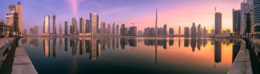 Dubai 'nin şehir manzarası ve panoramik Business Bay manzarası ve sabahları gökdelenlerin su üzerindeki yansıması, BAE.