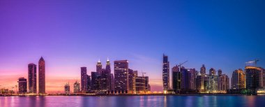 Cityscape Dubai ve gökdelenler su yansıma mor gündoğumu, BAE sırasında iş Körfezi'nin panoramik