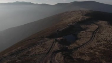 4x4 numaralı aracın yol dışına sürüşü, seyahat merkezleri macera yolculukları konsepti inanılmaz DRone çekimi. arka plandaki dağlar, toprak yol, araç kullanma, 4K Ukrayna.