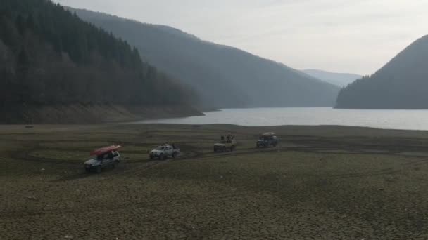 观看在沙道上行驶的狩猎车。4x4公路以外的空中车辆沿着干旱的沙漠山区附近的砾石小径行驶. — 图库视频影像